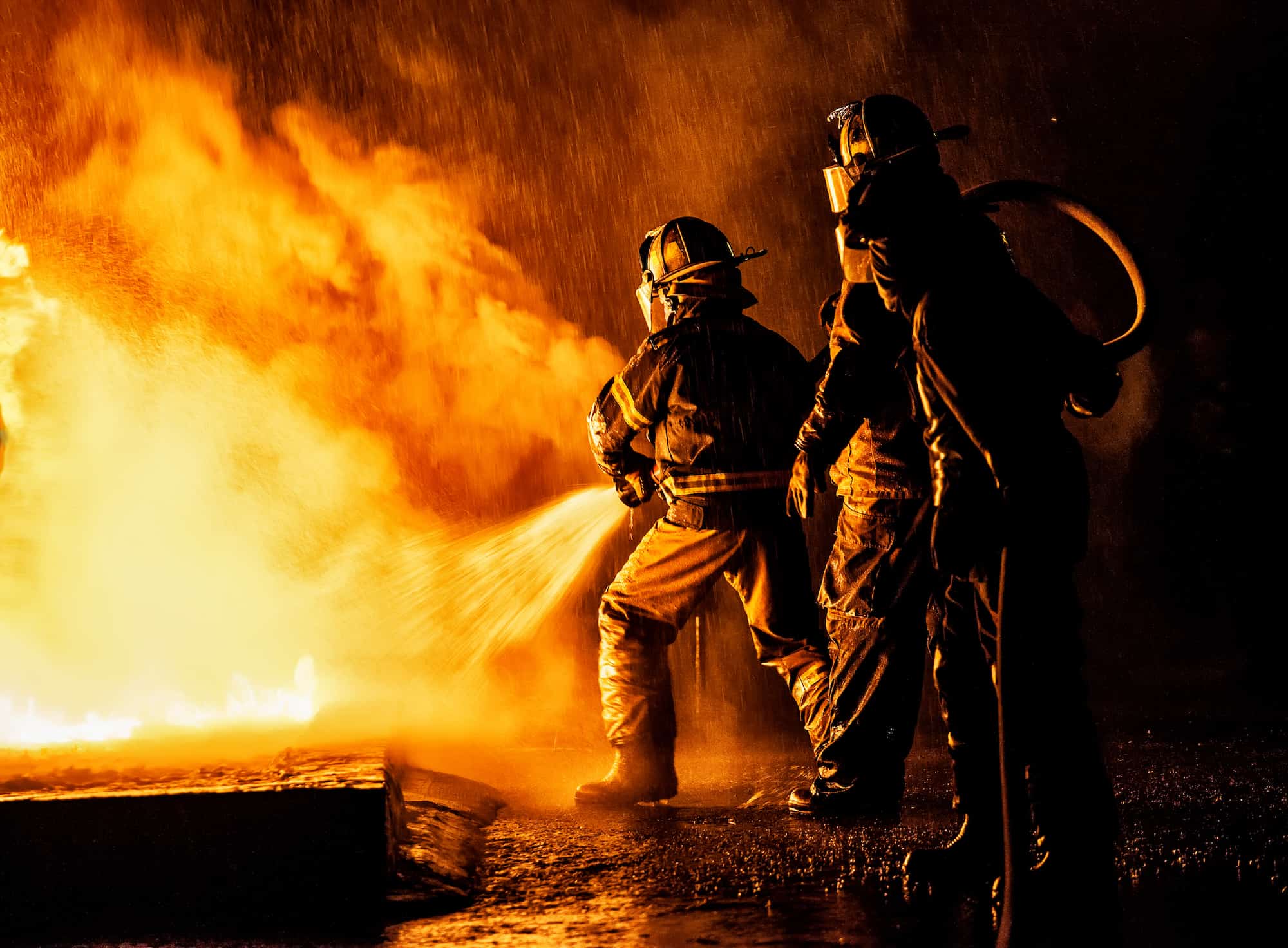 Johannesburg, South Africa - August 26, 2016: Two firefighters fighting a fire with a hose and water